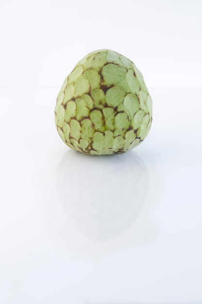 Custard apple reflected on a glass table against white background with copy space