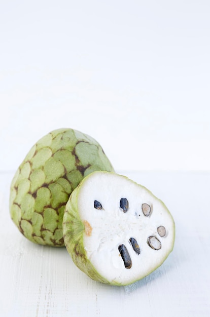 Custard apple reflected on a wooden table against white background with copy space