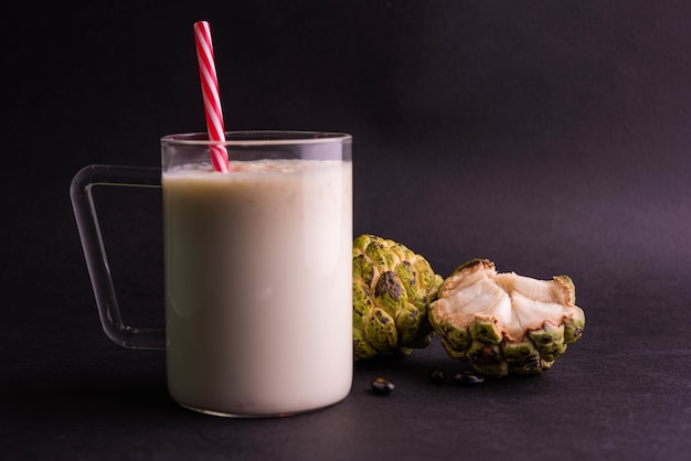 Custard Apple or Sitafal Milk Shake served in a glass with whole fruit over moody background. Selective focus