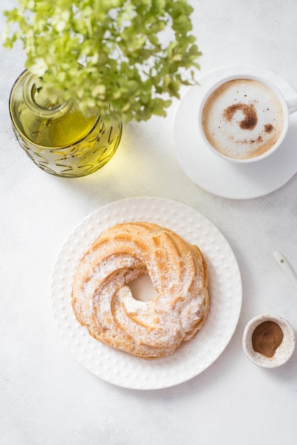 Custard cake eclair with coffee and hydrangeas on gray background