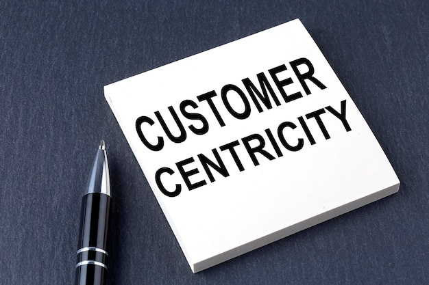 CUSTOMER CENTRICITY text on the sticker with pen on the black background