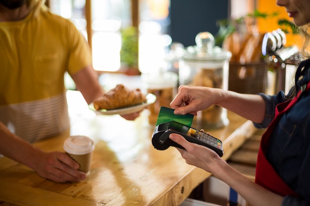 Customer making payment through credit card at counter in coffee