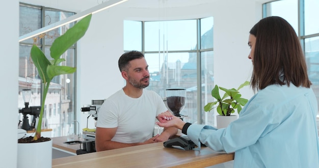 Customer paying with an NFC contactless smartwatch with a card machine Paying in a coffee shop by a smartwatch Technology