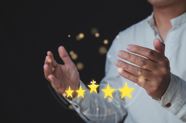 Customer review concept Among hands there are five stars for Excellent job Close up shot with some noise and film gain The man wears white shirt and gold light bokeh