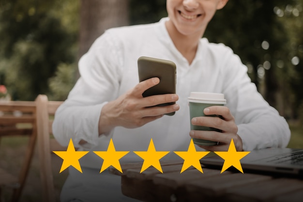 Customer service concept. Man with 5 stars score on his phone. Online ranking system.