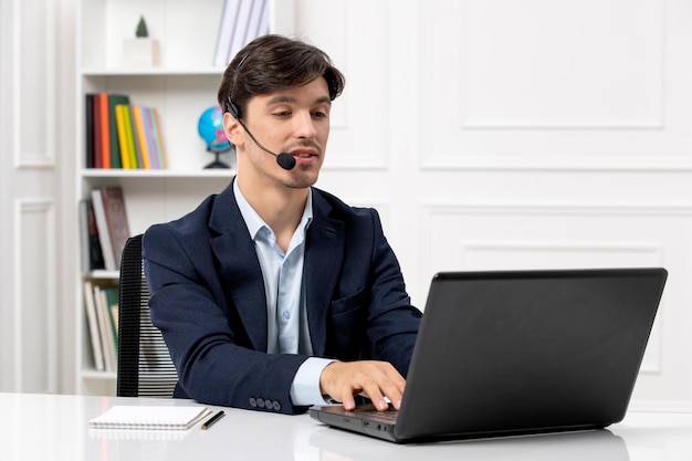 Customer service handsome guy with headset and laptop in suit typing on computer