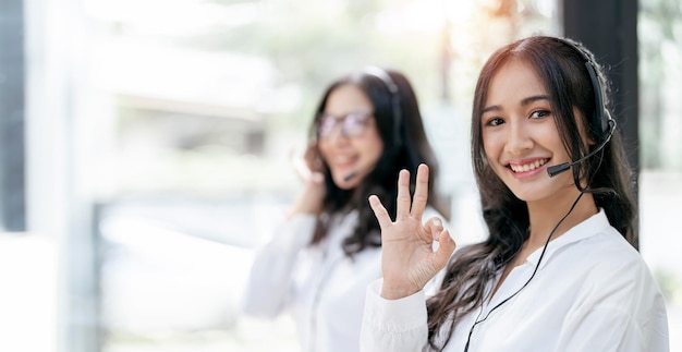 Customer support phone operator in headset showing ok okay or zero hand sign gesture smiling and looking at camera