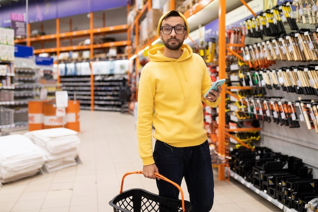 Customer with shopping cart and phone in hardware store