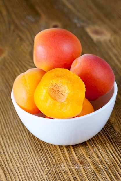 Cut apricots in a glass white bowl, delicious and healthy fruits, apricots red and yellow, food close-up