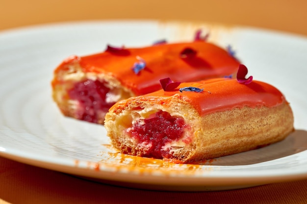 Cut in half eclair with berry filling and custard in a plate Closeup shallow depth of field