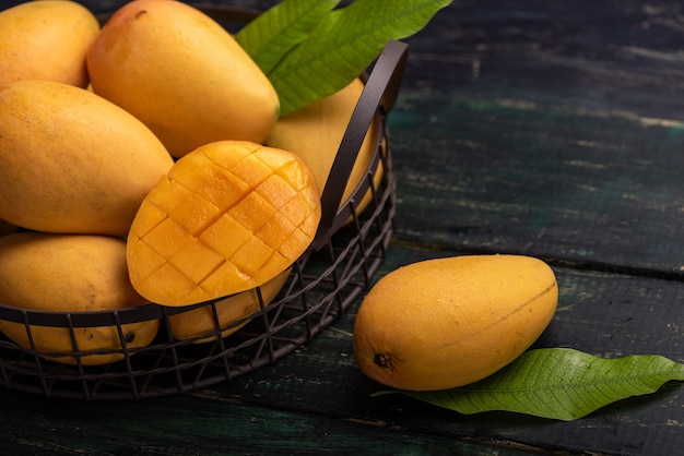 Cut and intact mangoes in the dark background