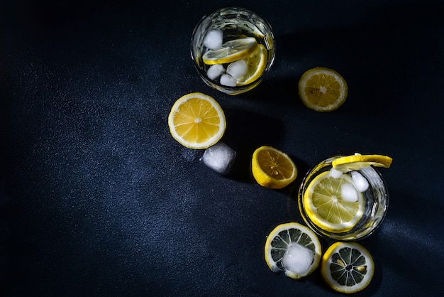 cut lemons with lemon slices and ice cubes against dark background. Top view. Close-up