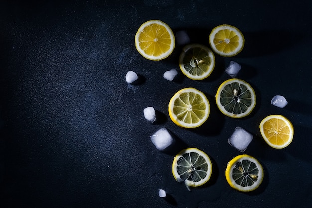 cut lemons with lemon slices and ice cubes against dark background. Top view. Close-up