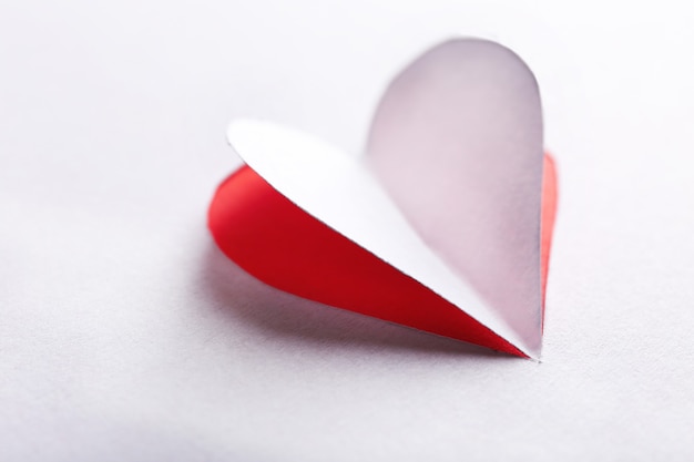 Cut out white paper heart on red background