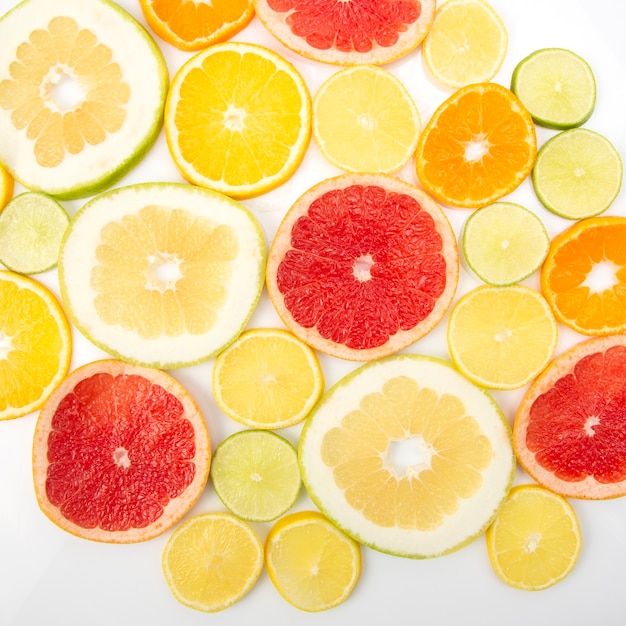 Cut pieces of different citrus fruits on white surface