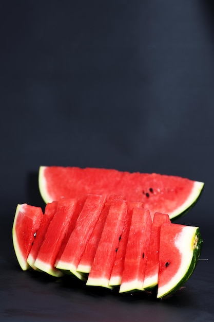 Cut pieces of red ripe delicious juicy watermelon on a black background