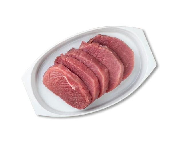 Cut raw eye round meat over white plate with seasonings isolated over white background.