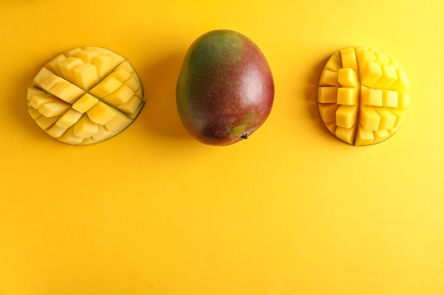 Cut ripe mangoes and space for text on color background, top view