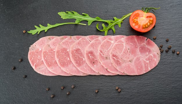 Cut sausage from ham on a wooden background