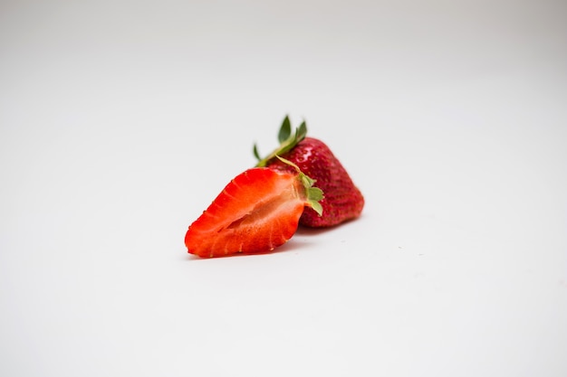 Cut strawberries on a white space with free space. Whole red strawberries and one half.