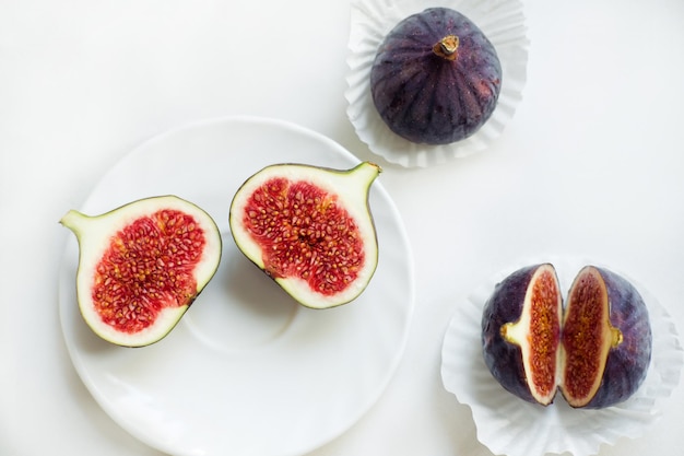 Cut and whole figs on a plate On a white background Flat lay Top view Copy space