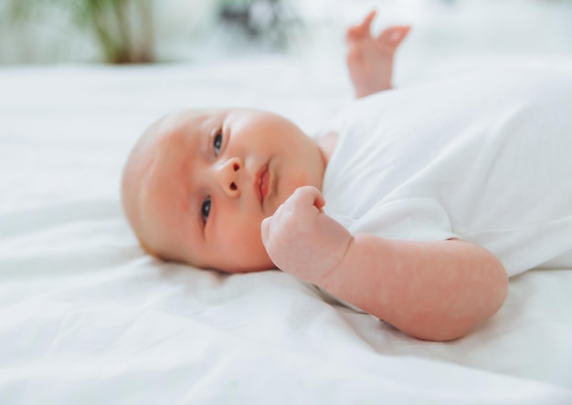 Cute 2monthold baby lying on the bed natural bed linen delicate baby skin