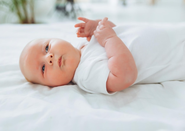 Cute 2monthold baby lying on the bed natural bed linen delicate baby skin