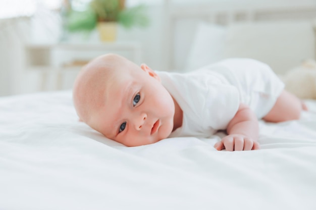 Cute 2monthold baby lying on the bed natural bed linen delicate baby skin