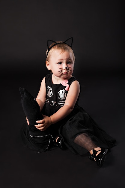 Cute aby girl in cat costume against black background