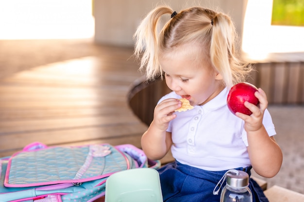 Cute adorable Caucasian toddler baby girl sitting and eating