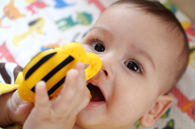 Cute adorable newborn baby playing with colorful rattle toy baby with teether six months old lovely baby portrait on white with teether toy