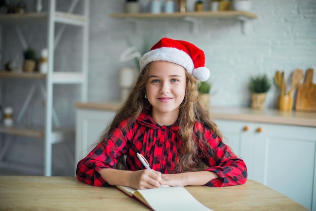 Cute adorable smiling girl in santa claus hat at home