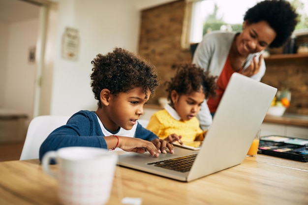 Cute African American boy using laptop at home