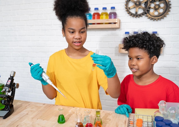 Cute afro hair girl and brother kids study science with test chemical in glassware