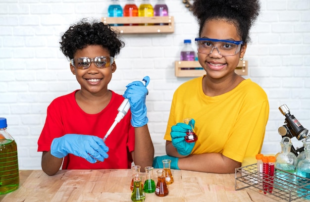 Cute afro hair girl and brother kids study science with test chemical in glassware