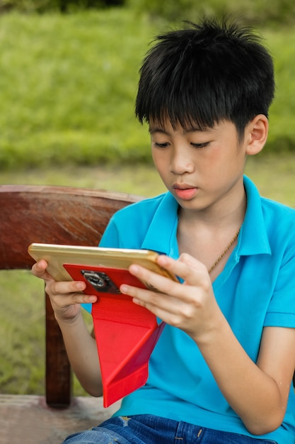 A cute Asia boy attention to playing tablet in free time.