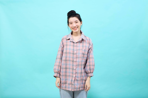 Cute asia girl smiling wearing a casual plaid shirt standing and feeling happiness and confident on blue background