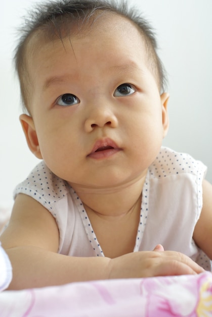 Cute Asian baby lying on the floor. Little Asian infant playing on the floor.