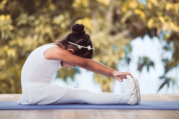 Photo cute asian child girl doing stretching exercises and practicing a ballet