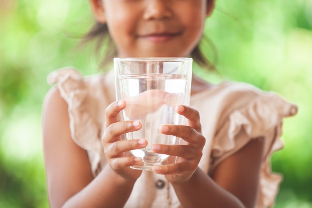 Photo cute asian child girl like to drink water and holding glass of fresh water