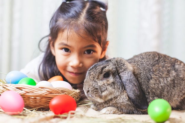 Cute asian child girl playing with cute Holland rabbit with love and tenderness at easter festive