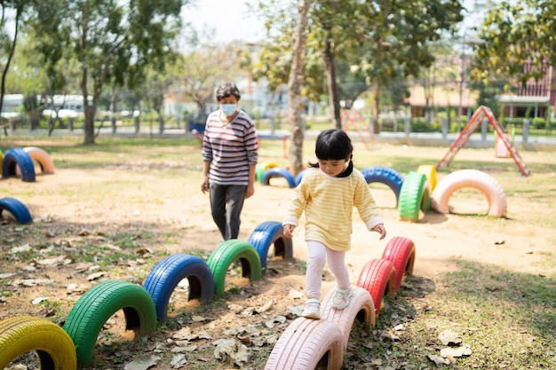 Cute asian girl and mother smile play on school or kindergarten yard or playground Healthy summer activity for children Little girl climbing outdoors playground Child playing outdoor playground