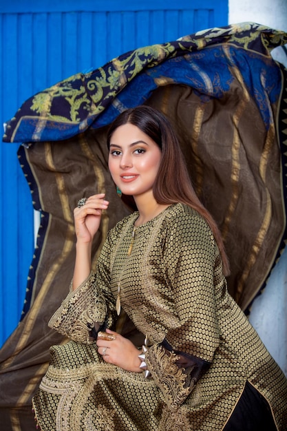 Photo cute asian girl side pose wearing traditional dress waving dupatta in background