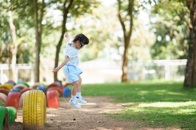 Cute asian girl smile play jumping on school orkindergarten yard or playground Healthy summer activity for children Little asian girl climbing outdoors at playground Child playing at playground