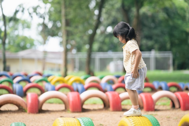 Cute asian girl smile and play on school or kindergarten yard or playground Healthy summer activity for children Little asian girl climbing outdoors at playground Child playing on outdoor playground