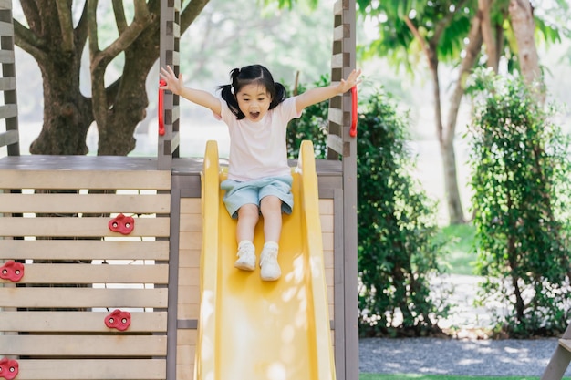 Cute asian girl smile play on school or kindergarten yard or playground Healthy summer activity for children Little asian girl climbing outdoors at playground Child playing on outdoor playground