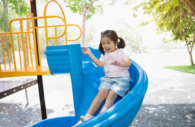 Cute asian girl smile play on school or kindergarten yard or playground Healthy summer activity for children Little asian girl climbing outdoors at playground Child playing on outdoor playground