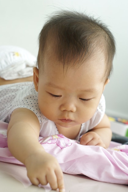 Cute Asian infant baby lying on the floor and write some thing on the floor.