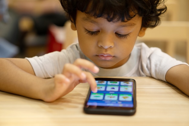 Cute asian little boy is playing a game on smartphone