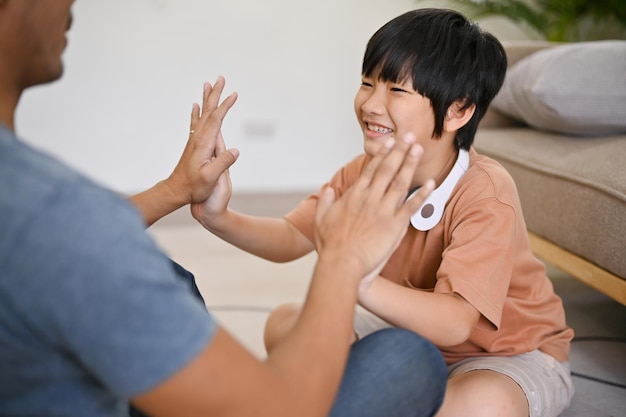 Cute Asian little boy playing with his dad spending fun family games time in the living room